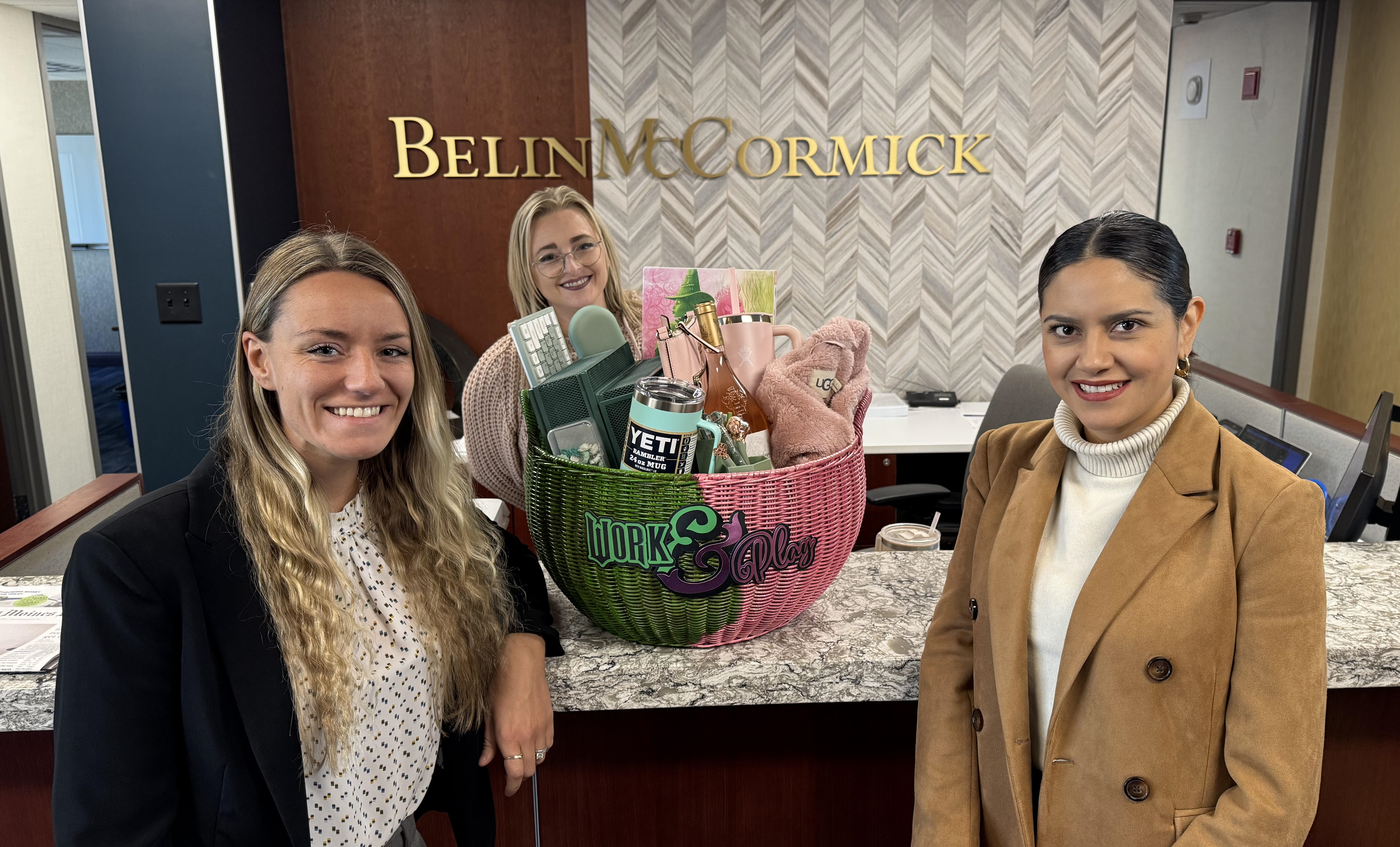 Three women stand in front of a green and pink basket f